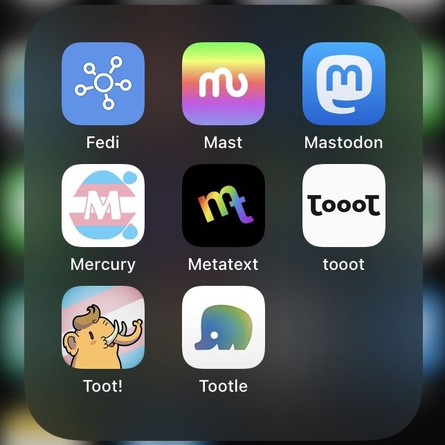 iOS folder opened up to 8 icons in a 3-by-3 grid (with a gap at the bottom right). The icons are:
Fedi, a blue icon with a blandly corporate stick-and-circle representation of a small network.
Mast, a stylised lowercase ‘m’ in the shape of an elephant, this variant on a rainbow background.
Mastodon, another blue icon, with the official mastodon logo, a white simplified elephant head or speech bubble, with a blue curved lowercase ‘m’ overlaid.
Mercury, a very odd outlined uppercase ‘M’ on stop of an irregularly shaped blob, with two small blobs beside it, this variant in trans flag colours.
Metatext, a black icon, with another variant of the elephant logotype, here combining lowercase ‘m’ and ‘t’, this variant with rainbow colouring.
tooot, a white icon with the word ‘tooot’ in black, the tau-like ‘t’s bookmarking three smaller raised ‘o’s.
Toot!, a cute cartoon mastodon, this variant on an inclined trans flag background.
Tootle, a simple rounded chunky elephant shape in blue-to-green shading on a white background.
